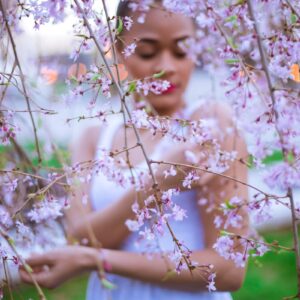 woman in white dress sitting on white flower field during daytime